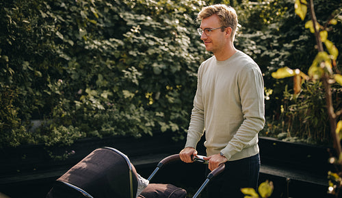 Father pushing baby carriage in park