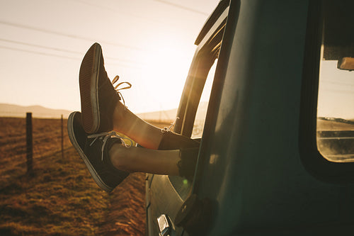 Close up of legs hanging out of a car on highway