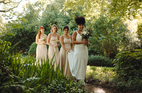 Bride and bridesmaids walking together in a scenic outdoor wedding setting