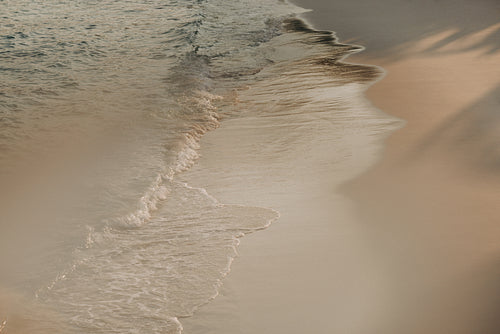 Peaceful beach scene with gentle waves lapping against the sandy shore at sunset