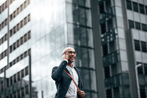 Businessman talking over mobile phone walking outdoors