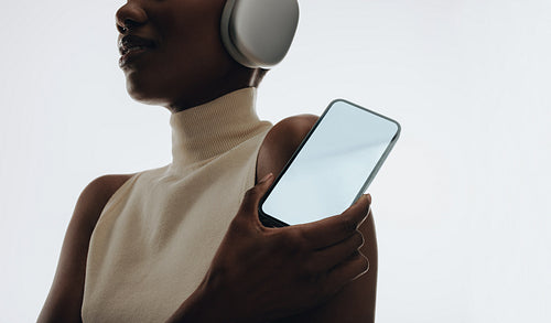 Woman with headphones holding smartphone in a modern minimalistic style
