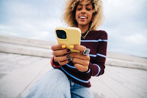 Young woman texting on smartphone and smiling outdoors