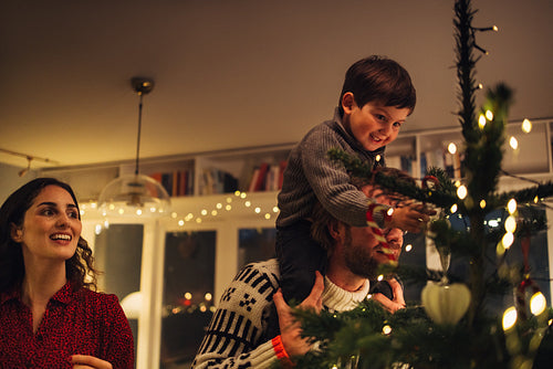 Boy decorating Christmas tree with parents