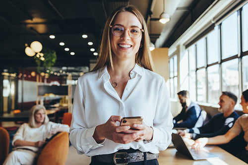 Young businesswoman holding a smartphone in a co-working space