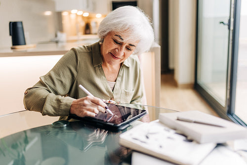 Creative senior woman drawing on a digital tablet
