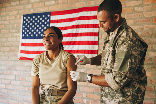 Male nurse rubbing a soldier's arm with cotton before an injecti