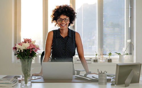 Happy businesswoman standing at her desk