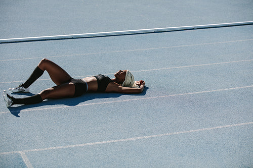 Woman athlete relaxing on running track after training
