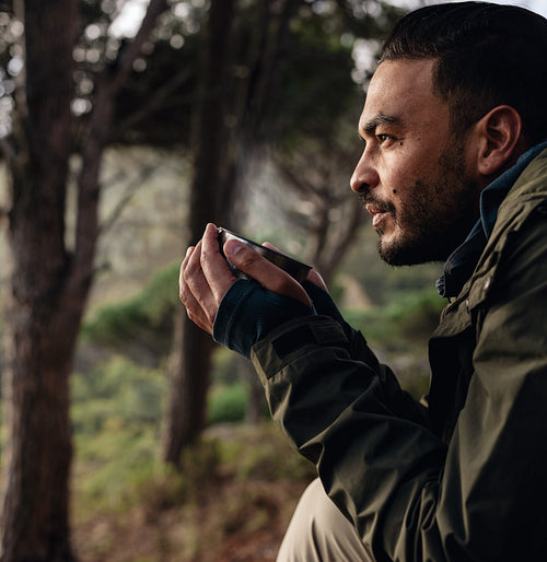 Young male hiker drinking coffee