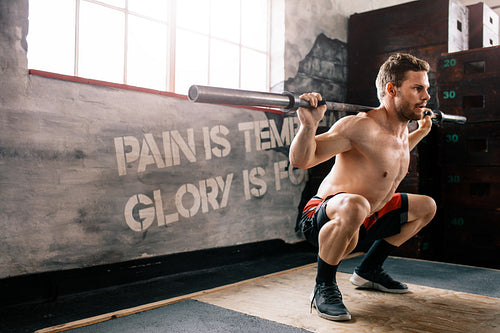 Muscular man at crossfit gym lifting barbell