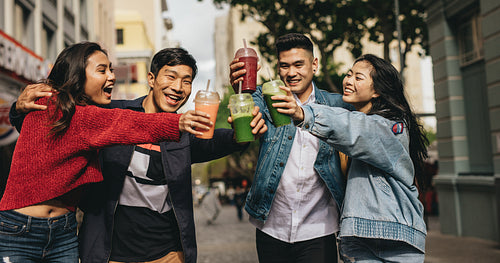 Cheerful friends toasting drinks on the street