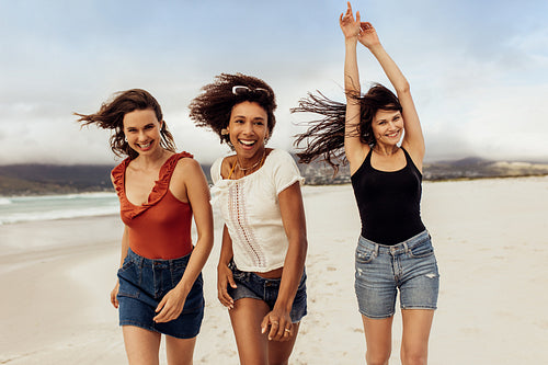 Playful female friends running on the beach