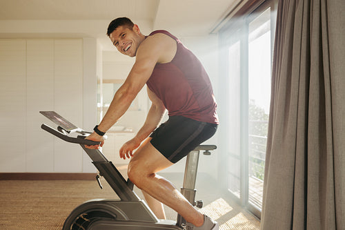 Indoor cycling: Young man enjoys high-tech training in home gym