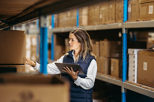 Warehouse worker checking shipping labels while holding a tablet
