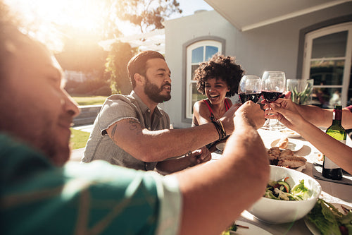Group of friends toasting drinks alfresco