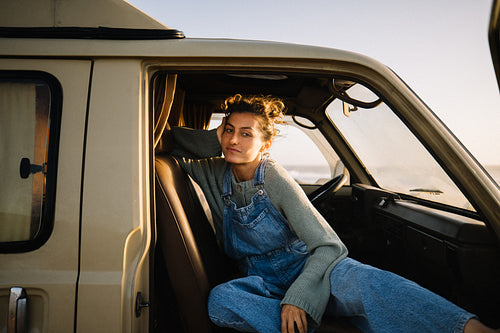 A woman relaxes in a vintage van while resting on the seat during a calm road trip