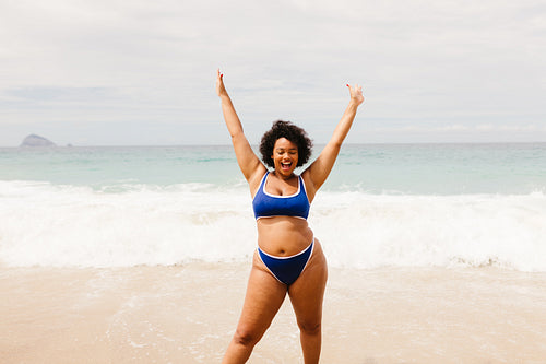Happy plus size woman in a bikini celebrating and having fun at the beach