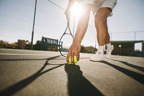 Man bending down to pick a tennis ball