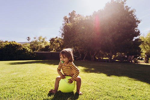 Kid sitting on a ball in a park