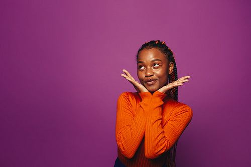 Confident young woman with stylish two-tone braids poses against vibrant purple background