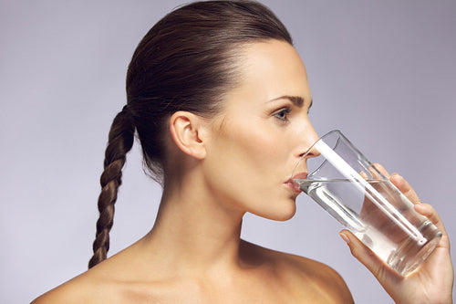 Young beautiful woman drinking a glass of mineral water