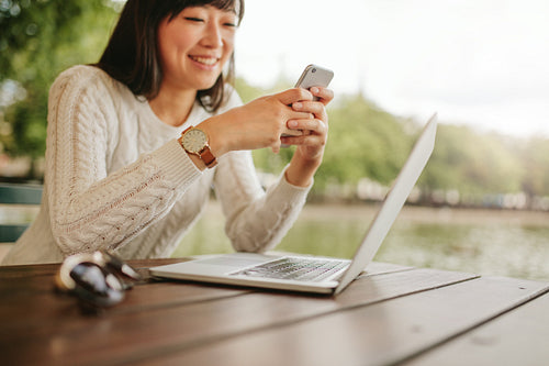 Woman using cell phone at cafe