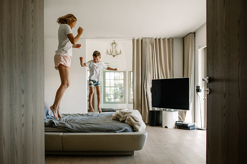 Mother and son jumping on bed