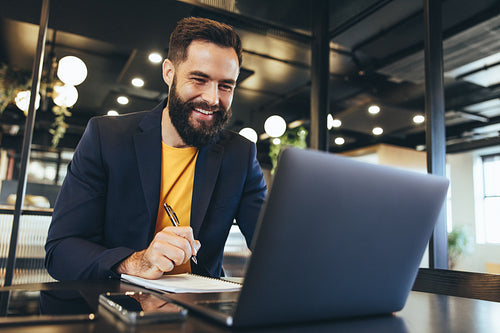 Entrepreneur writing notes during a virtual meeting