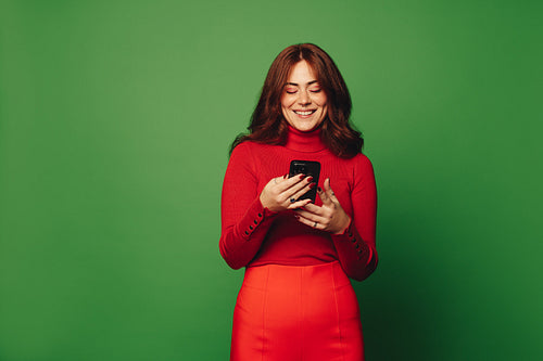 Happy woman making a video call with her smartphone on a green background