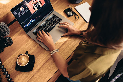 Young female vlogger editing her vlog on computer.