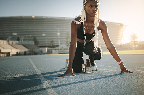 Sprinter using a starting block to start her sprint on a running track