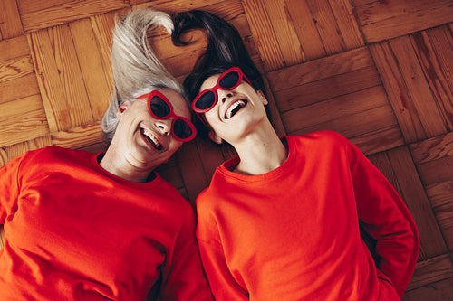 Top view of mother and daughter lying on floor with heads together