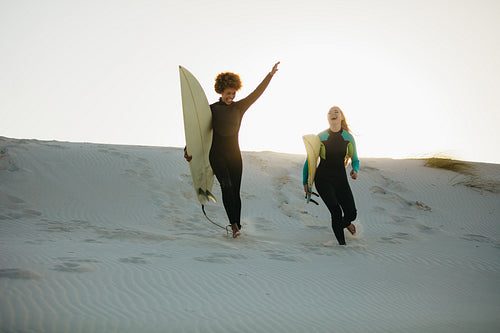 Surfers running down the beach