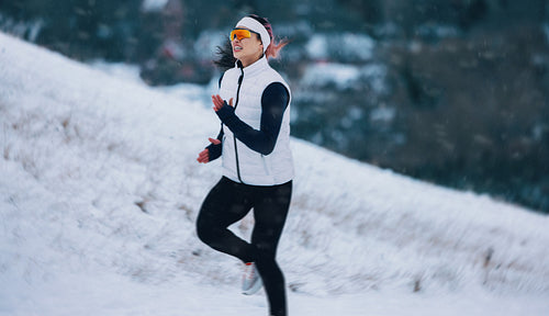 Uphill running takes the woman across a snowy mountain slope in winter