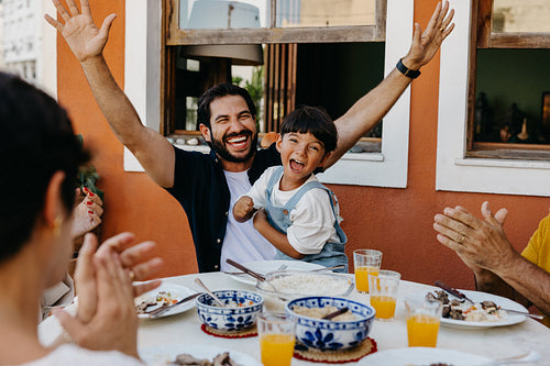 Smiling Brazilian family enjoying a churrasco meal outdoors with joyful expressions