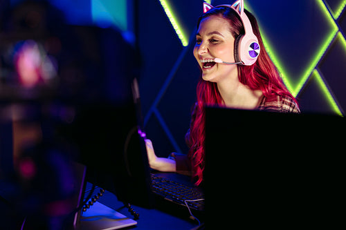 Woman enjoying playing a video game and live streaming for her fans