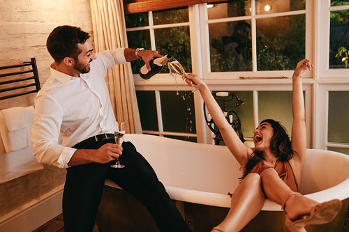 Ecstatic young couple having fun with champagne