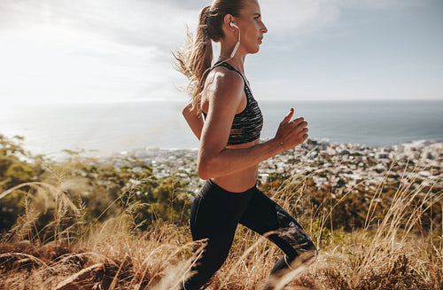 Fit woman running through mountain trail