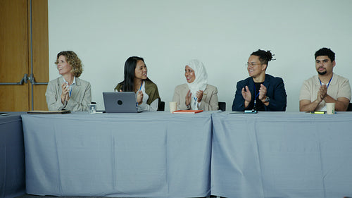 Professionals smiling, laughing, and clapping together at a panel discussion
