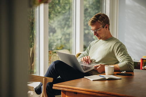 Man sitting at home using laptop
