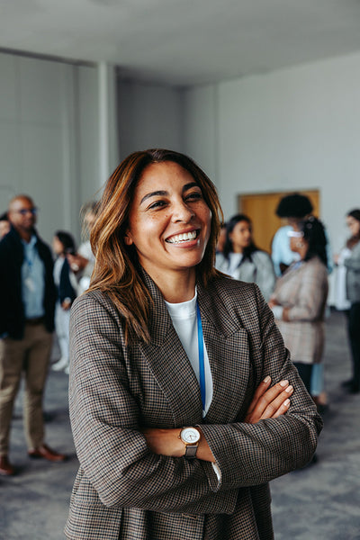 Confident female leader smiling with arms crossed in a business environment with diverse colleagues