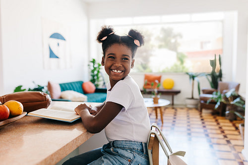 Black girl practicing reading comprehension with a book at home