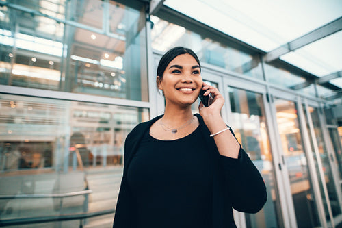 Beautiful young woman on business trip talking on cellphone at airport