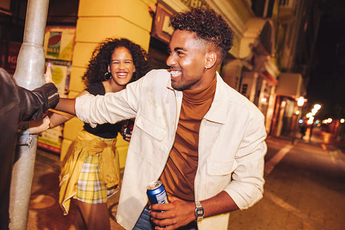 Joyful friends playing around a pole at night