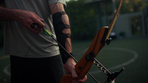 Skilled male archer holding a wooden bow, preparing to shoot an arrow with precision and focus