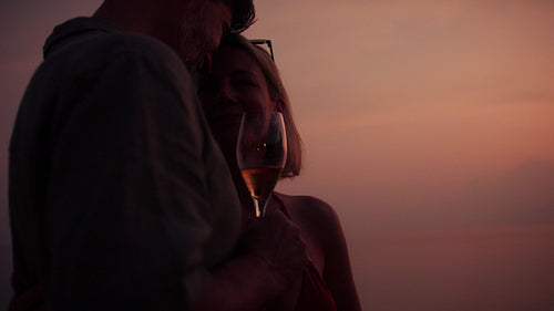 A mature couple holding wine glasses during golden hour