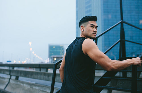 Muscular man climbing up steps outdoors