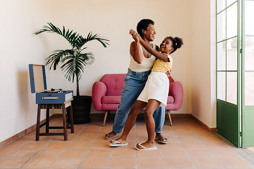 Mother and daughter dance at home with vinyl record player