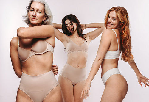 Three women in studio posing and stretching in nude underwear